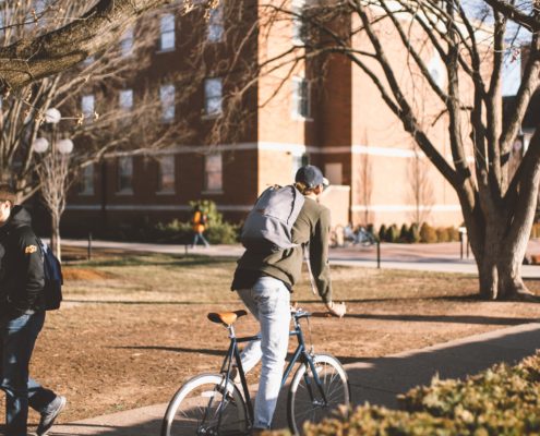 Student navigating through a college campus on a bike